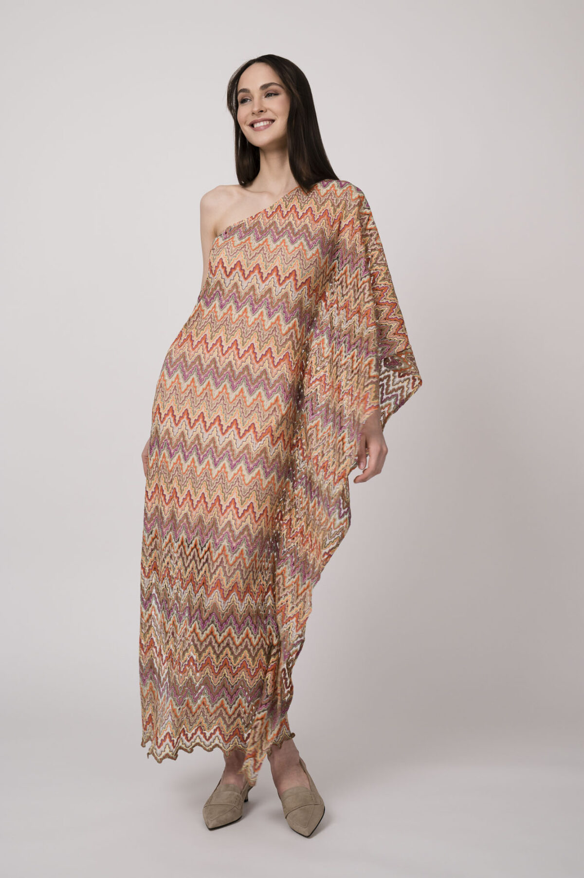 Model trägt ein oranges gemustertes, asymmetrisches Strickkleid von Ana Alcazar.