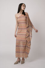 Model trägt ein oranges gemustertes, asymmetrisches Strickkleid von Ana Alcazar.