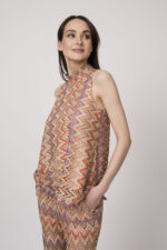 Model trägt ein oranges gemustertes, Strickoberteil von Ana Alcazar.