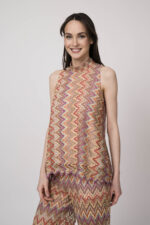 Model trägt ein oranges gemustertes, Strickoberteil von Ana Alcazar.