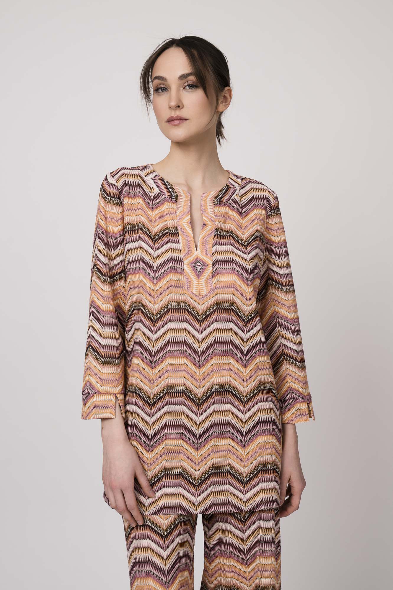 Model trägt ein oranges gemustertes, Strickoberteil von Ana Alcazar.