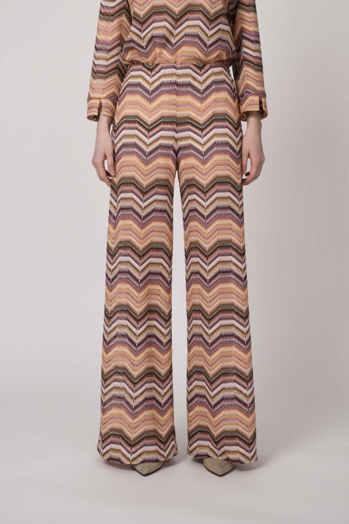Model trägt eine orange gemusterte Strickhose von Ana Alcazar.
