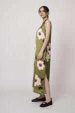 Model trägt ein ärmelloses grünes Kleid mit hellen großen Blumenprints der Marke Ana Alcazar.