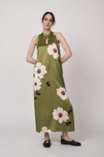 Model trägt ein ärmelloses grünes Kleid mit hellen großen Blumenprints der Marke Ana Alcazar.
