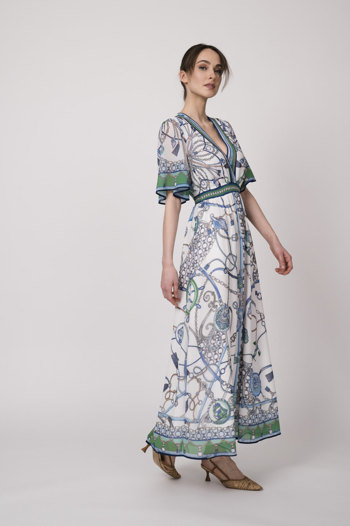 Model trägt ein weiß, blau und grün gemustertes Kleid der Marke Hale Bob.