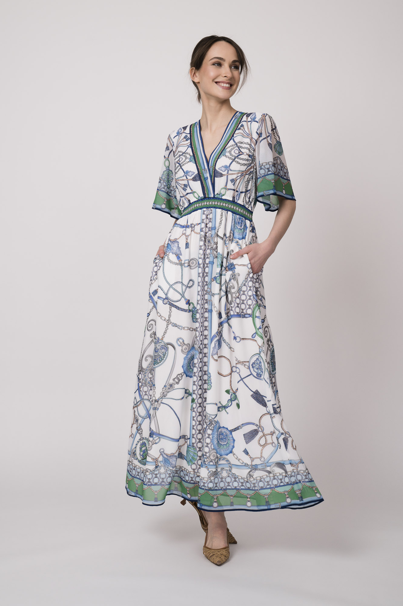 Model trägt ein weiß, blau und grün gemustertes Kleid der Marke Hale Bob.