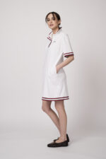 Model trägt ein weißes Kleid am Polo-Shirt-Stil mit blau-weißen Details der Marke Joop!