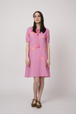 Model trägt ein pinkes kurzes Kleid mit Palmen-Stickereien der Marke Grace.