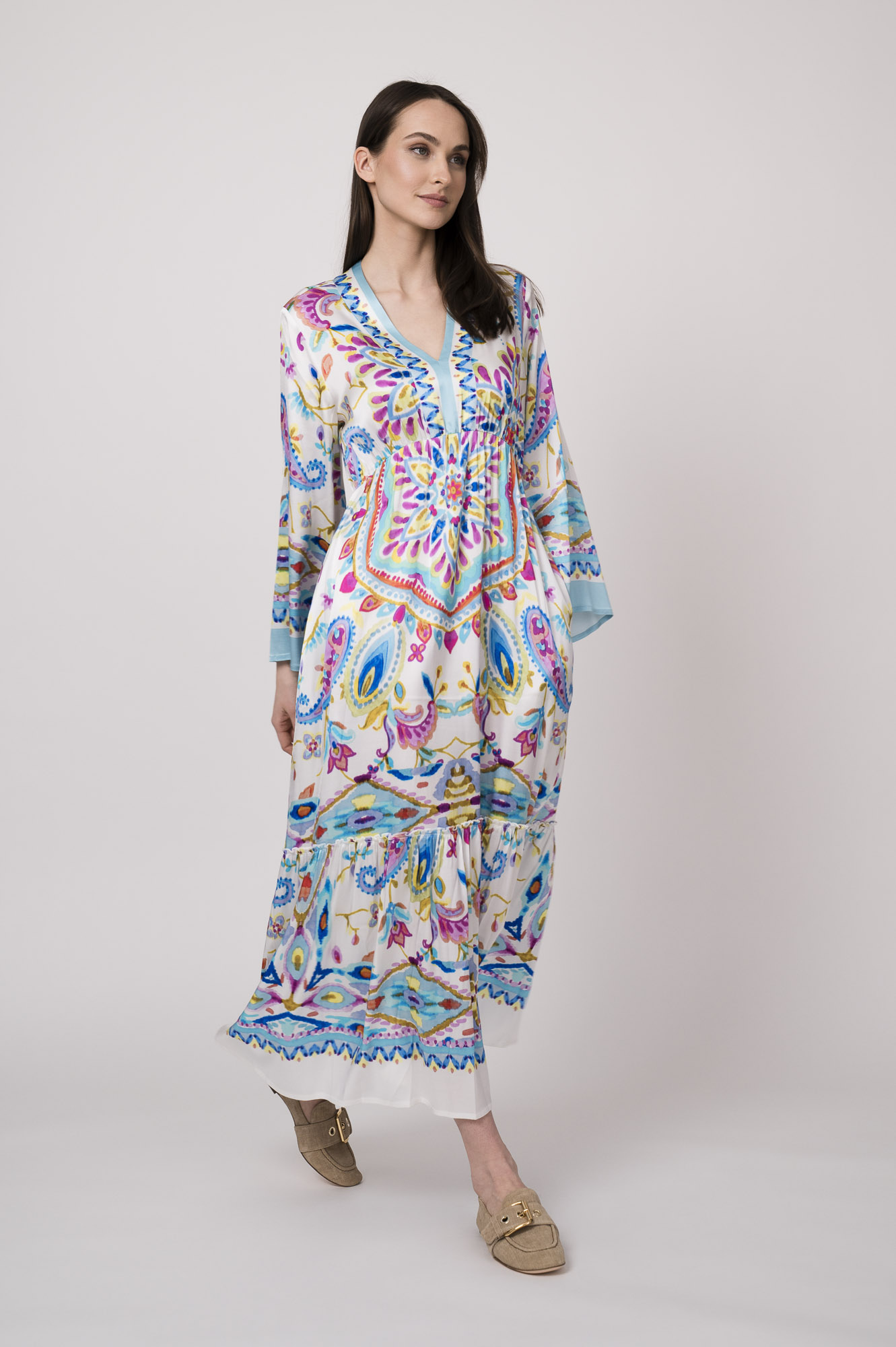 Model trägt ein weißes Kleid mit bunten Mustern der Marke Grace.