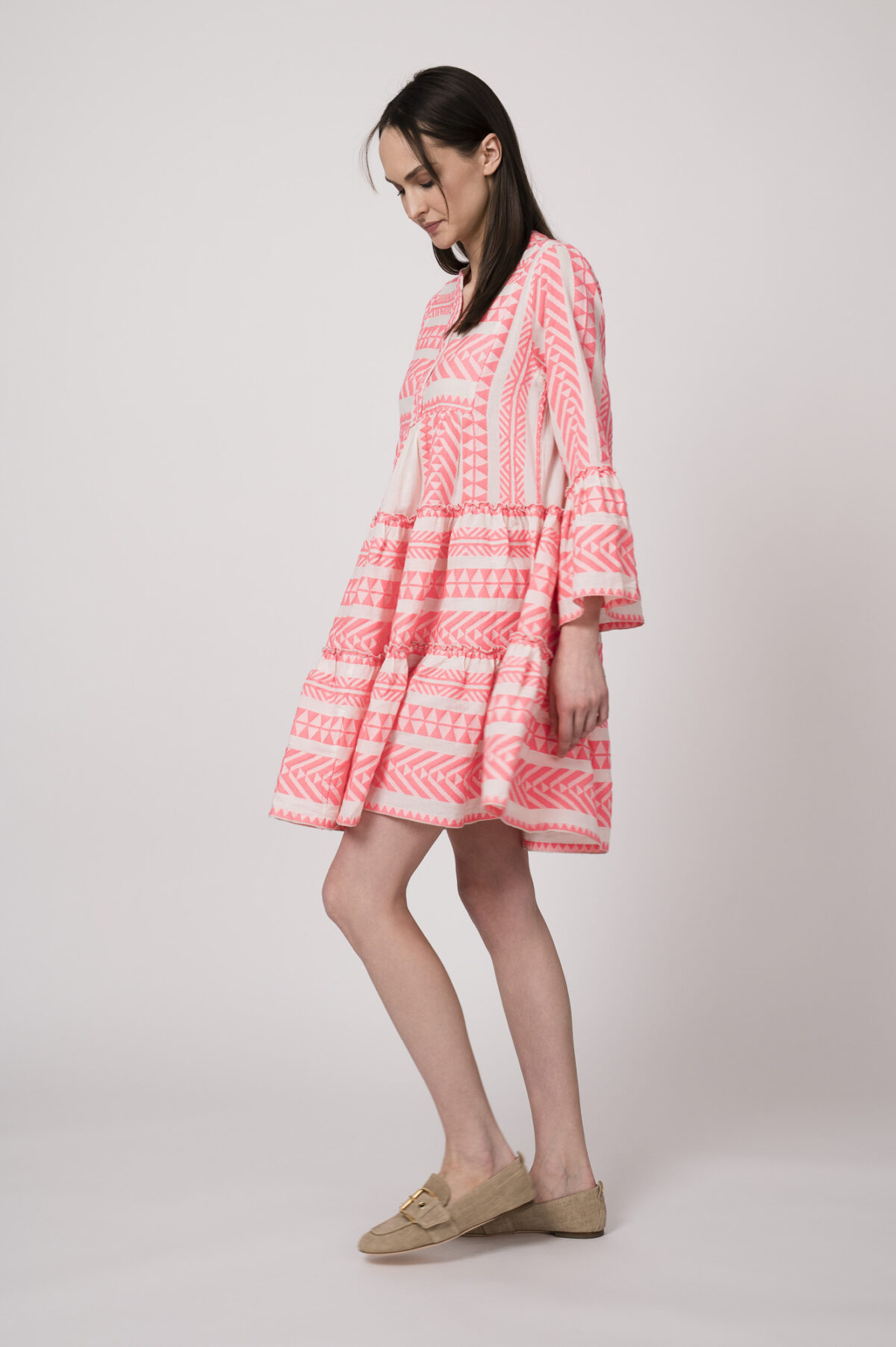 Model trägt ein neon-pink und beige gemustertes, kurzes Kleid der Marke Devotion.