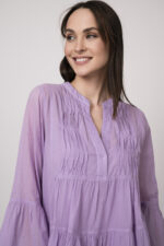 Model trägt ein flieder-farbiges, kurzes Kleid der Marke Devotion.