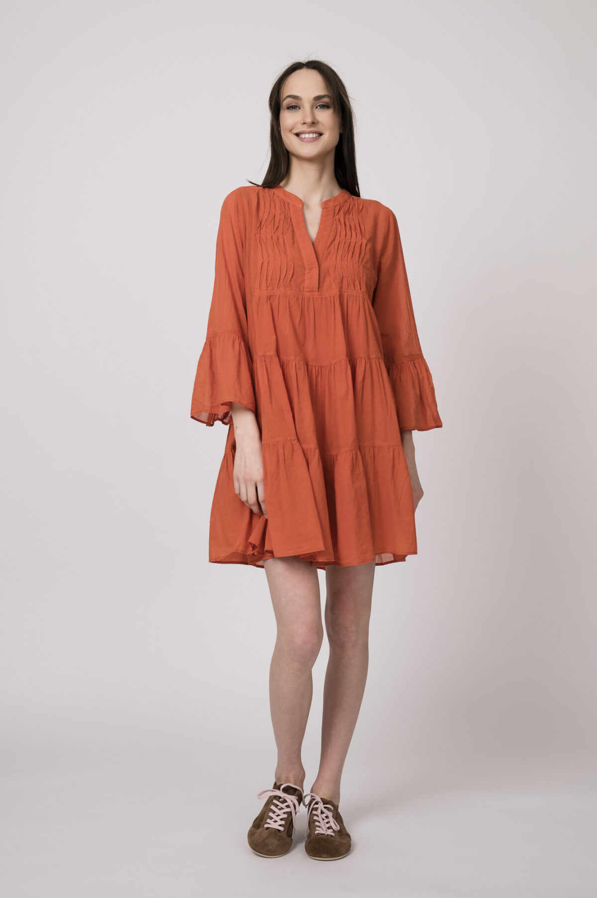 Model trägt ein oranges, kurzes Kleid der Marke Devotion.