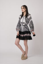 Model trägt ein schwarz-weiß gemustertes, kurzes Kleid der Marke Devotion.
