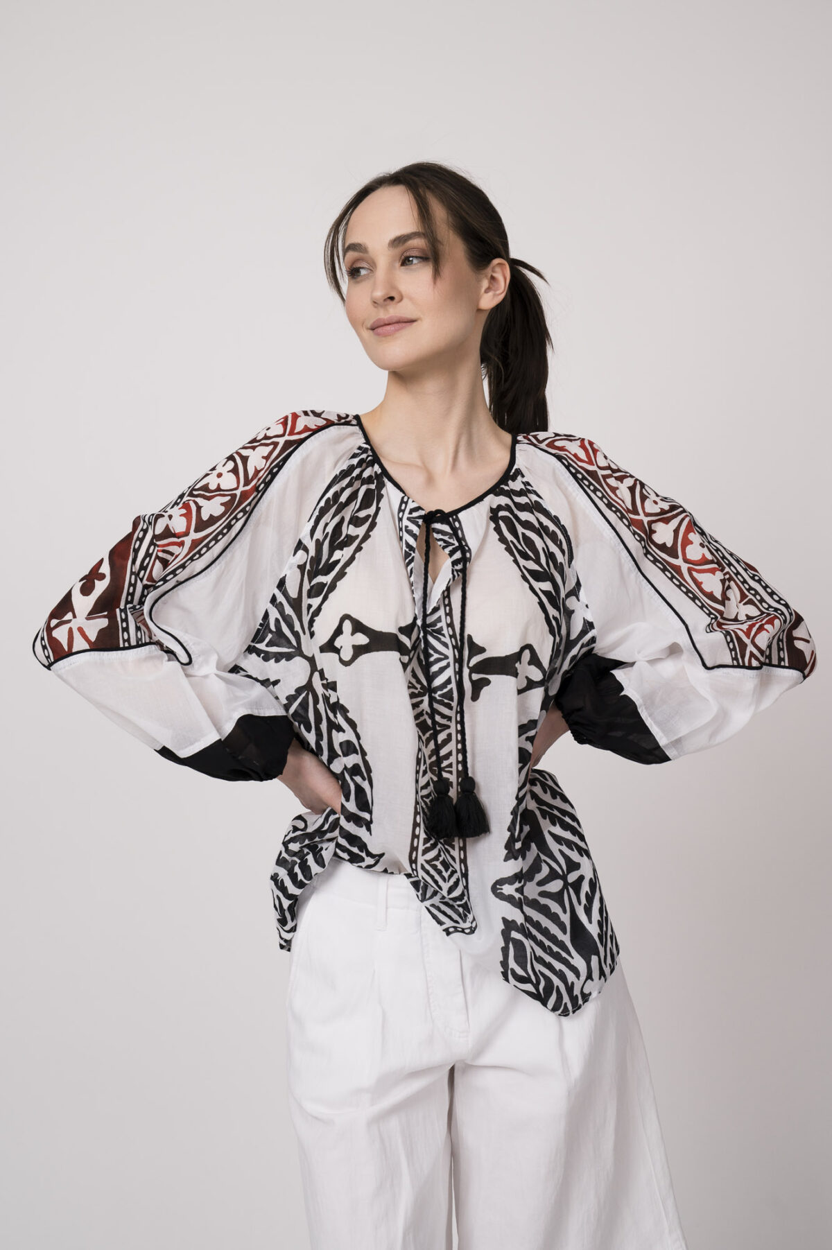 Model trägt eine schwarz-weiß gemustertes Bluse der Marke Devotion und eine Bermuda Shorts der Marke Luisa Cerano.