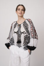 Model trägt eine schwarz-weiß gemustertes Bluse der Marke Devotion und eine Bermuda Shorts der Marke Luisa Cerano.