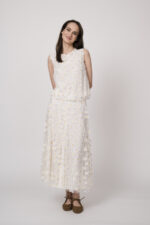 Model trägt ein weißes Top und einen weißes Rock mit Tüll und Gänseblümchen-Applikationen der Marke Luisa Cerano.