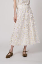 Model trägt einen weißen Rock mit Tüll und Gänseblümchen-Applikationen der Marke Luisa Cerano.