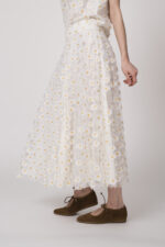 Model trägt einen weißen Rock mit Tüll und Gänseblümchen-Applikationen der Marke Luisa Cerano.
