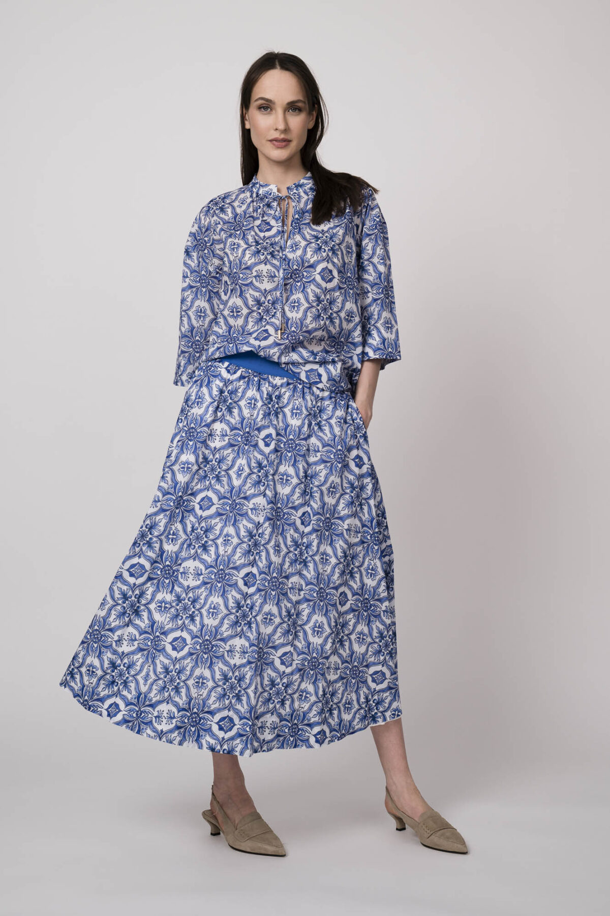 Model trägt eine blau-weiß gemusterte Bluse und einen blau-weiß gemusterten Rock der Marke Joop!