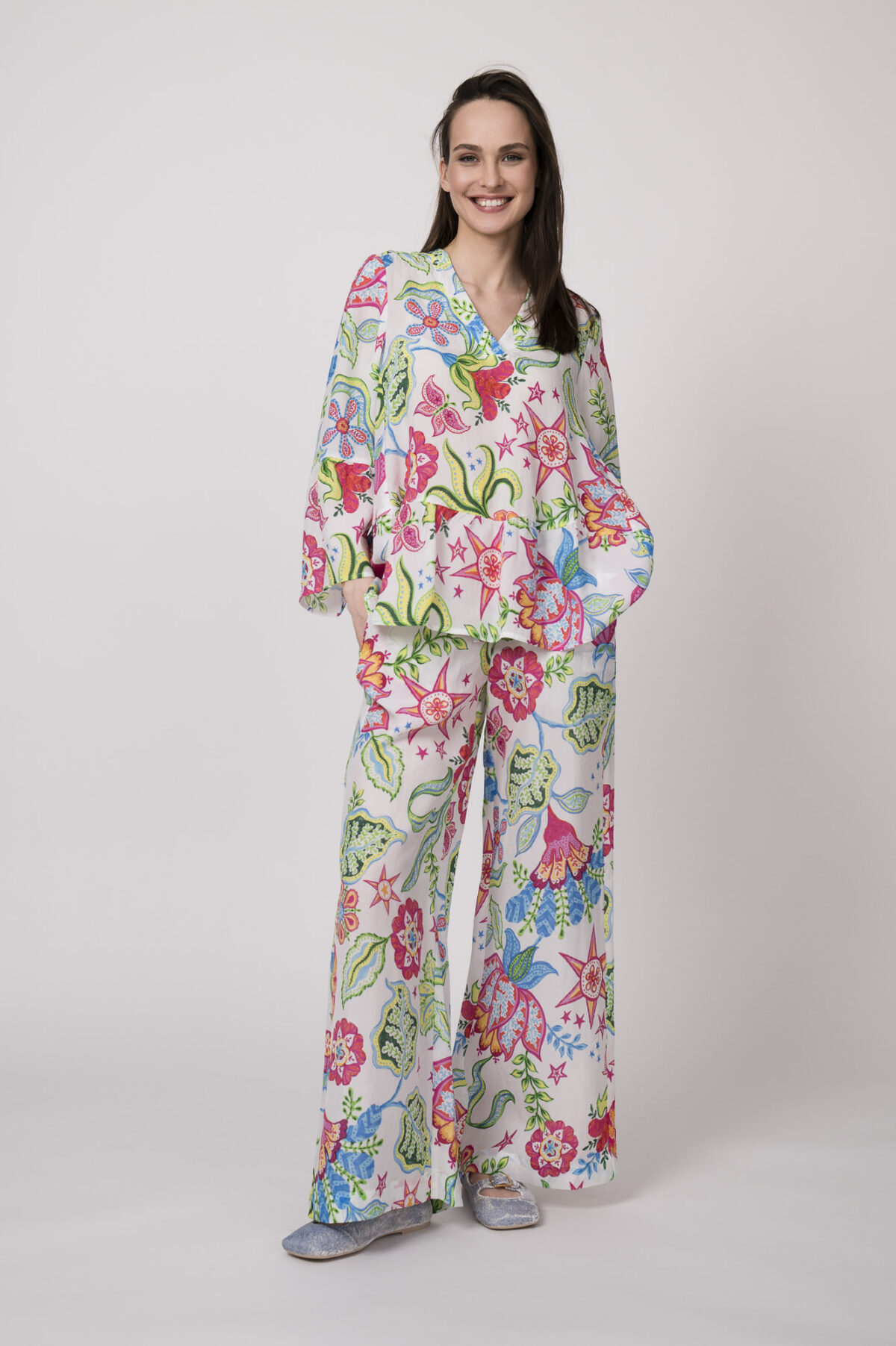 Model trägt eine bunt gemusterte Bluse und Hose der Marke Grace.