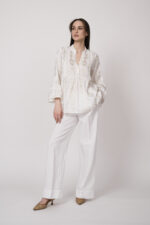 Model trägt eine weiße Tunika der Marke Grace und eine weiße Hose der Marke Masons‘.