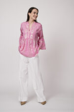 Model trägt eine pinke Tunika der Marke Grace und eine weiße Hose der Marke Masons‘.