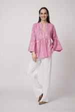 Model trägt eine pinke Tunika der Marke Grace und eine weiße Hose der Marke Masons‘.