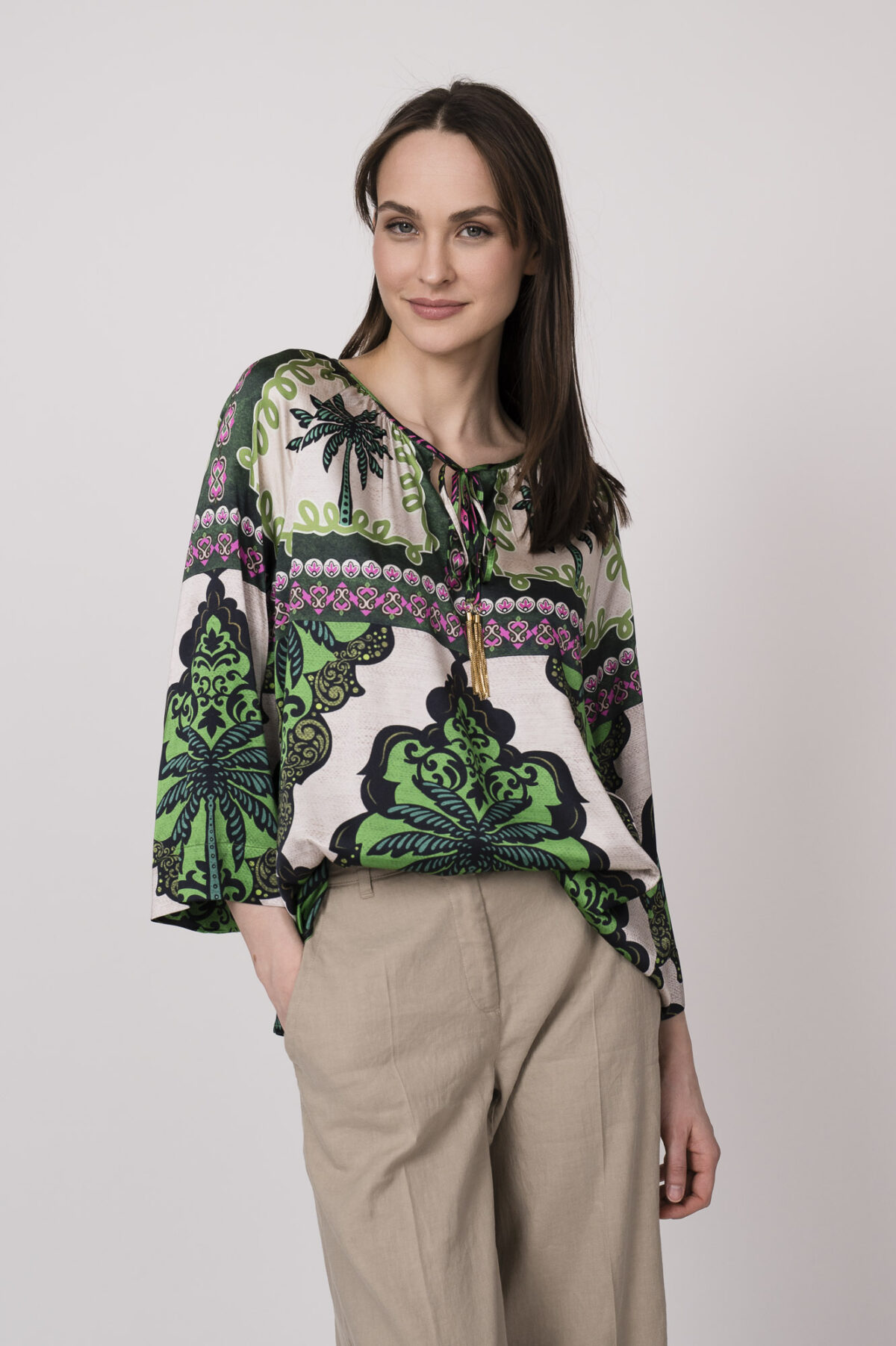 Model trägt eine grün, weiß und pink gemusterte Bluse der Marke Grace