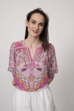 Model trägt eine pinke Bluse mit Print der Marke Hale Bob und eine weiße Shorts mit Cutouts der Marke 0039Italy.