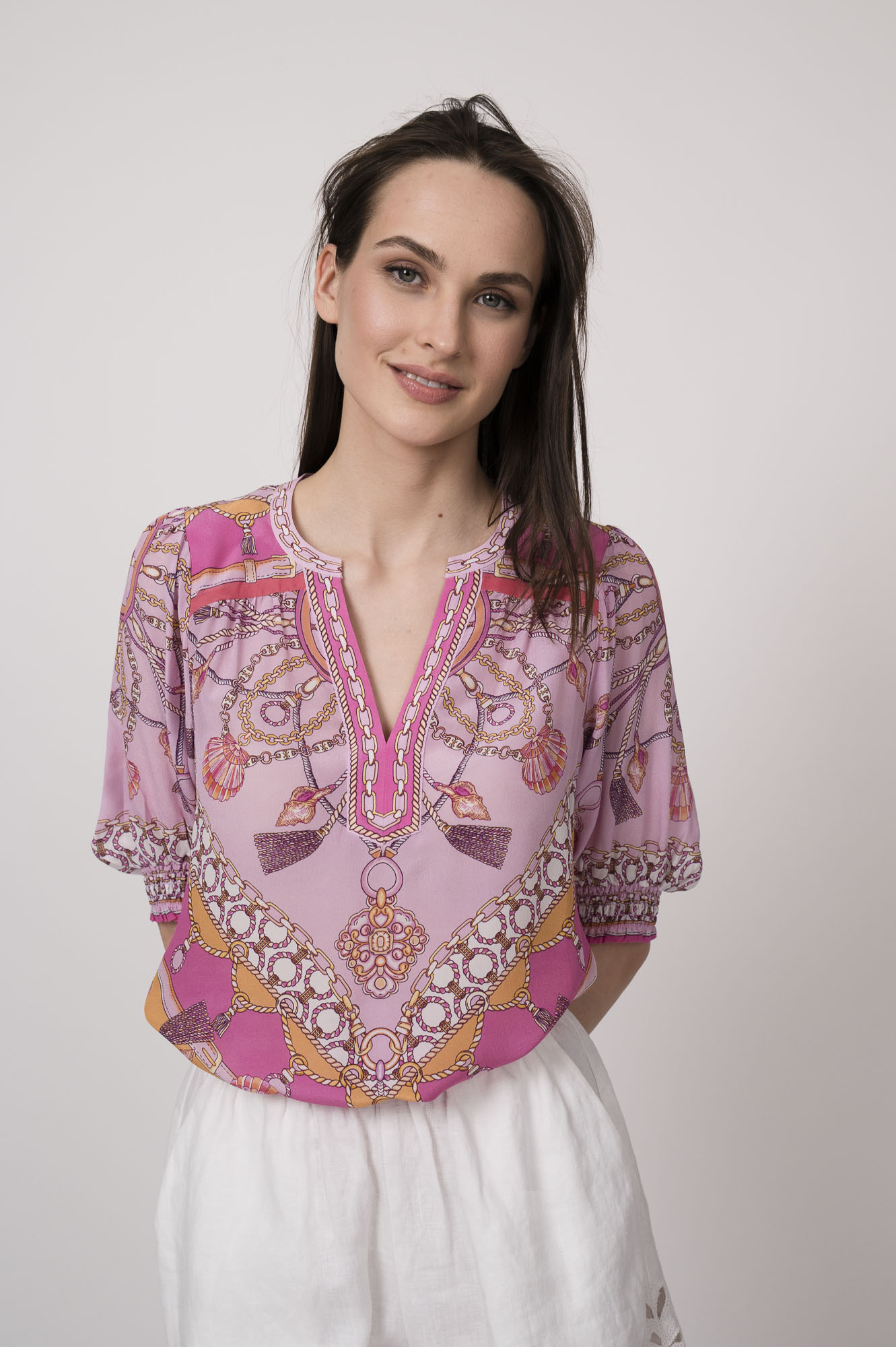 Model trägt eine pinke Bluse mit Print der Marke Hale Bob und eine weiße Shorts mit Cutouts der Marke 0039Italy.