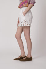 Model trägt eine weiße Shorts mit Cutouts der Marke 0039Italy.