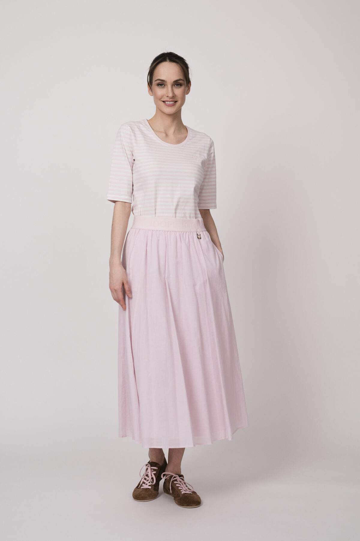 Model trägt ein weiß rosa gestreiftes Shirt und einen rosa Rock der Marke Joop!
