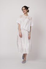 Model trägt ein weißes Oberteil und einen weißen Rock der Marke MeiMeij.