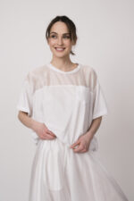 Model trägt ein weißes Oberteil der Marke MeiMeij.