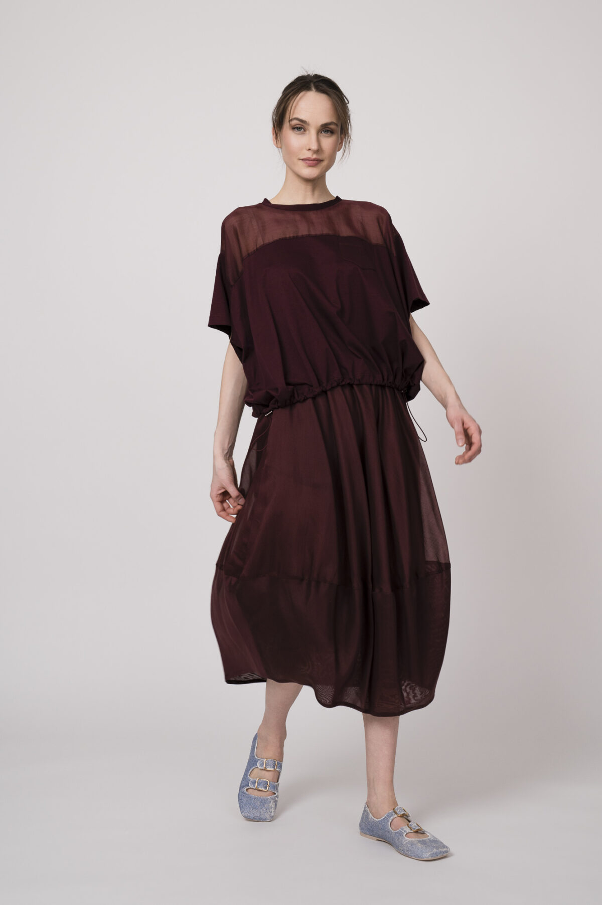 Model trägt ein bordeaux-farbiges Oberteil und einen bordeaux-farbigen Rock der Marke MeiMeij.