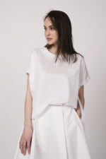 Model trägt ein weißes Oberteil der Marke MeiMeij.