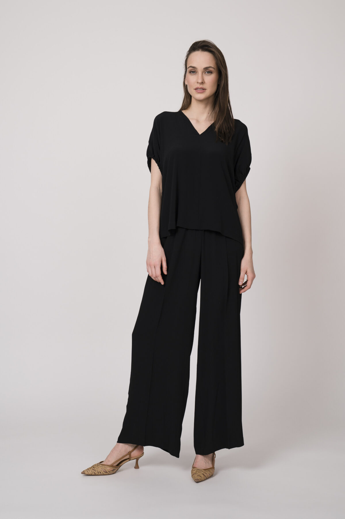 Model trägt ein schwarzes Oberteil und eine schwarze Hose der Marke MeiMeij.