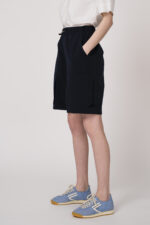 Model trägt eine marine-blaue Bermuda Shorts der Marke Lis Lareida.