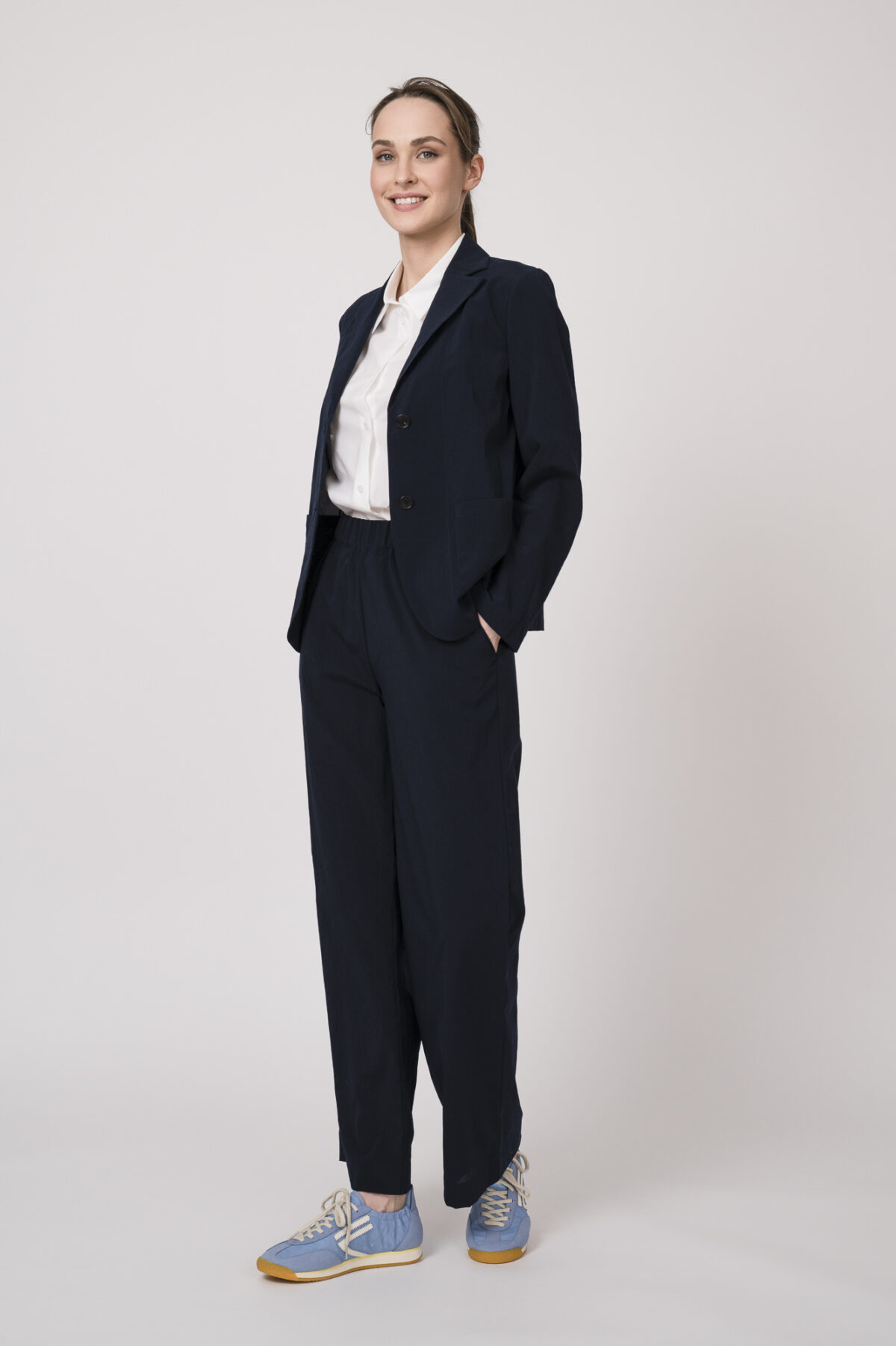 Model trägt einen marine-blauen Hosenanzug und eine weiße Bluse der Marke Lis Lareida.