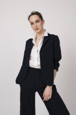 Model trägt einen marine-blauen Blazer und eine weiße Bluse der Marke Lis Lareida