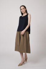 Model trägt ein marine-farbiges Top und einen schlamm-farbigen Rock der Marke Susanne Bommer.