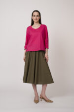 Model trägt eine pinke Bluse und einen olivgrünen Rock der Marke Susanne Bommer.