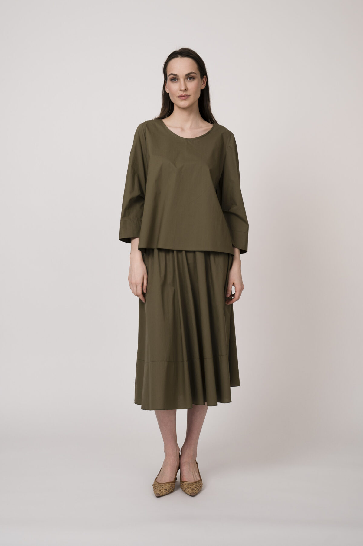 Model trägt eine olivgrüne Bluse und einen olivgrünen Rock der Marke Susanne Bommer.