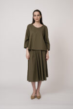Model trägt eine olivgrüne Bluse und einen olivgrünen Rock der Marke Susanne Bommer.