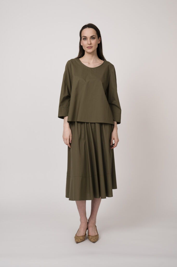 Model trägt eine olivgrüne Bluse und einen olivgrünen Rock der Marke Susanne Bommer.