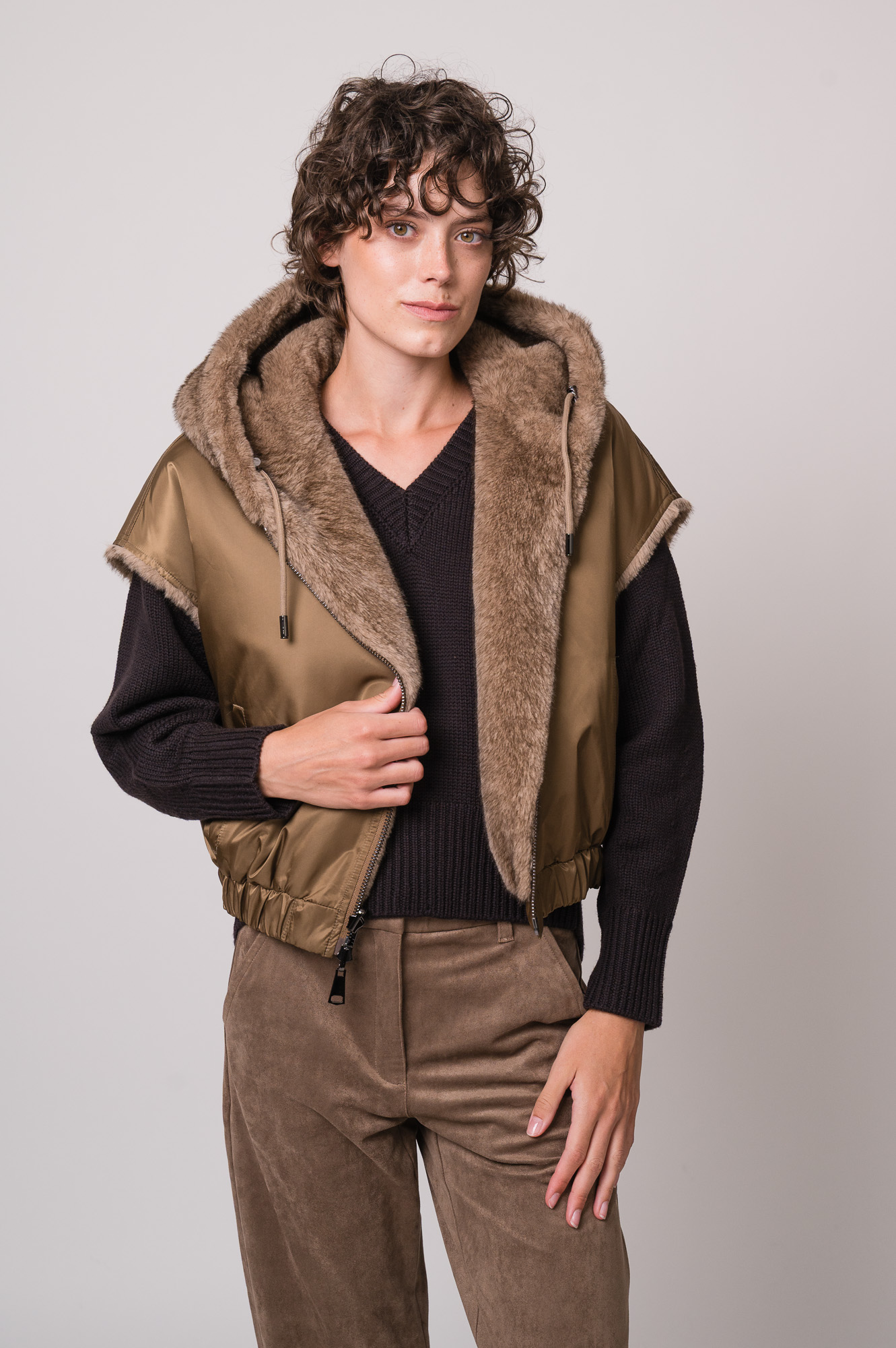 Model trägt ein braunes Cape der Marke Betta Corradi, einen dunkelbraunen Pullover der Marke Meimeij.