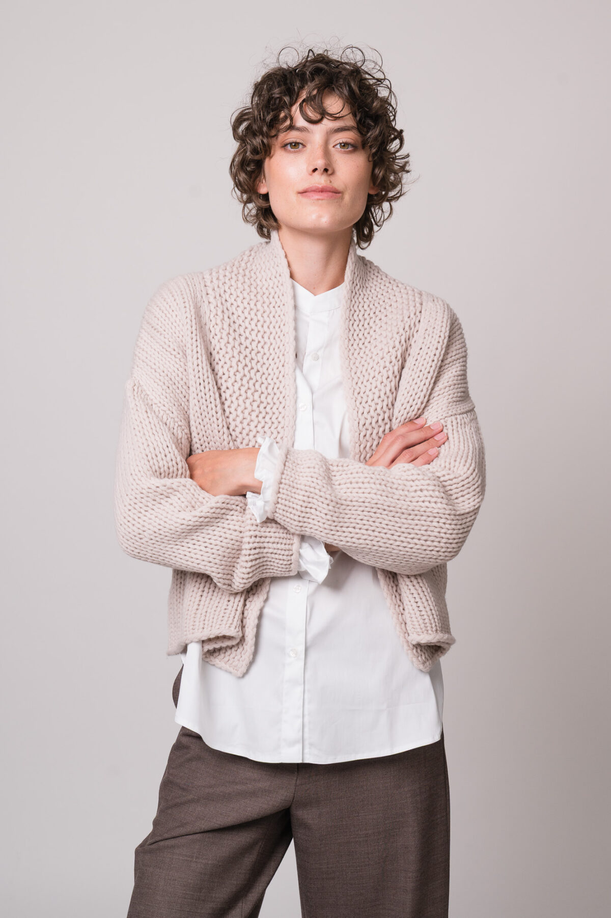 Model trägt eine weiße Bluse der Marke Rossana Diva, eine beige Strickjacke der Marke FFC