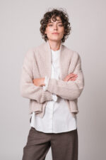 Model trägt eine weiße Bluse der Marke Rossana Diva, eine beige Strickjacke der Marke FFC
