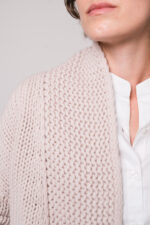 Model trägt eine weiße Bluse der Marke Rossana Diva, eine beige Strickjacke der Marke FFC
