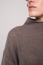 Model trägt einen taupe Pullover der Marke FFC und eine braune Hose der Marke Lis Lareida.